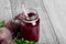 Close-up of a vegetable smoothie. Red beetroot drink in a jar on a wooden table background. Ripe whole beets and leaves.