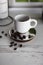 Close up vertical photo of coffee beans and a white ceramic espresso cup