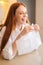 Close-up vertical shot of laughing young woman playing pops bubble wrap to calm herself sitting at table in kitchen.