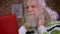 Close-up very tired face of senior caucasian man with white long beard and hair is massaging his neck and looking at red