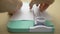 Close up video of a boy cutting a blank sheet of paper with a paper cutter mint on a wooden table