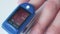 Close-up video. Doctor measures saturation through finger with electronic device with display. Static frame.