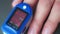 Close-up video. Doctor measures saturation through finger with electronic device with display. Static frame.