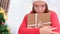 Close up video of a girl in a Santa hat with sad facial expression holding the gift and does not want to give yo anyone.