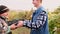 Close up video of one young farmer man passing the basket of ripe gathered grapes to another farmer adult man in the