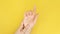 Close up video, unrecognizable woman massaging hand suffering from joint pain on a yellow background. lady touching
