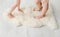 Close up view of 2 young girls sisters children standing with bare feet toes on very soft woolen sheepskin rug carpet.