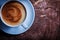 Close up view from above coffee with foam and cinnamon in white ceramic cup on vintage cross section tree trunk