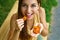 Close up view from above of a woman eating dried apricots outdoors. Healthy food concept