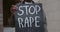 Close up view of african american male hands holding carton placard with stop rape writing at city street. Activist