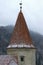 Close up view of ancient tower with red tile roof against mountain with winter forest. Famous Bran Castle, also called Dracula`s