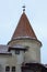 Close up view of ancient tower with red tile roof in the snow, against cloudy sky. Famous Bran Castle, also called Dracula`s