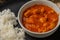 Close up view of appetizing butter chicken curry dish from classic Indian cuisine. Black round plate background. Exotic spicy dish