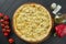 Close up view on Appetizing Hawaiian pizza with melted cheese, chicken and pineapple on dark wooden background in a restaurant.