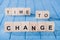 close up view of arranged wooden blocks into time to change phrase on blue wooden surface