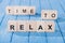 close up view of arranged wooden blocks into time to relax phrase on blue