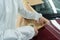 Close-up view of auto painter`s hands who covering a car body before painting with masking tape and paper.