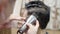 A close-up view of a barber does the hairstyle and trimming with trimmer and comb to guy. Commercial video