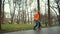 Close-up view of bearded male roller skater in orange jacket, skillfully skating and performing complex turns and tricks