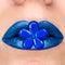 Close up view of beautiful woman lips with blue lipstick. Closed mouth. Cosmetology, fashion makeup. Jewellery flower
