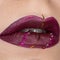 Close up view of beautiful woman lips with vinous purple matt lipstick. Cosmetology, fashion makeup. Jewellery on lips