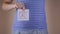 A close-up view of the belly of a pregnant woman in a blue T-shirt, which holds in her hands leaflets with the