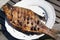 Close up view of big freshwater fish cooked on grill on big white plate.. Food background. Outdoor backgrounds.