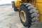 Close up view of the black rubber wheel of a yellow construction machinery