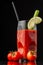 Close-up view of Bloody Mary cocktail glass with lime, celery and straw, on slate with cherry tomatoes, selective focus, on black