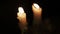 Close-up view of bright burning candles in a dark room. Warming cozy atmosphere from burning wax candles in the dark