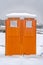 Close up view of a bright orange portable restroom in Daybreak Utah