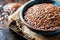 Close-Up View of Brown Flaxseeds in a Rustic Ceramic Bowl on a Wooden Table