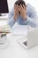 Close-up view of Caucasian businessman with heads in hands at his desk