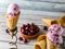 A close up view of a cherry ice cream cone in a stand with a bowl of cherries to the right.