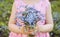 Close up view of child in pink party dress holding bouquet of Myosotis also known as forget me nots or scorpion grasses.