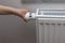 Close up view of child`s hand turning off thermostat on heating radiator to save energy.