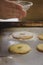 Close up view of children hands sprinkling sugar on top of homemade cookies on a rustic fountain