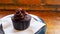 Close up view of chocolate cupcakes on black plate with brown wooden background