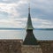 Close up view of a church roof with steeple and a lake view behind