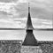 Close up view of a church roof with steeple and a lake view behind