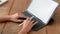 Close up view college girl typing on mock-up tablet while holding stylus on wooden desk