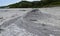 Close up view on crater of mud volcano. Slow flow of underground mud mixed oil, dirt & other liquids is flowing from volcano`s