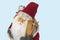 Close up view of a cute figure of Santa Claus with skis and a bag of gifts behind his back isolated on blue background. Sweden.