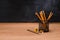 close up view of desk organizer with pencils and sharpener on wooden table in front of empty chalk board