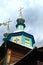 Close-up view of the dome of ancient wooden church against cloudy sky. Picturesque decorated facade by carved wooden platbands.