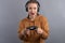 Close-up view of emotional woman using joystick and headphone on gray background. Concept of playing video game. Active