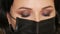 Close-up view of the face of young beautiful stylist woman beautician in black medical mask.