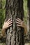 Close-up view of female hands embracing tree trunk