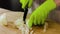 Close up view of female hands in green gloves cutting onion.