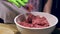 Close up view of female hands in green gloves working with chopped meat in white bowl. .